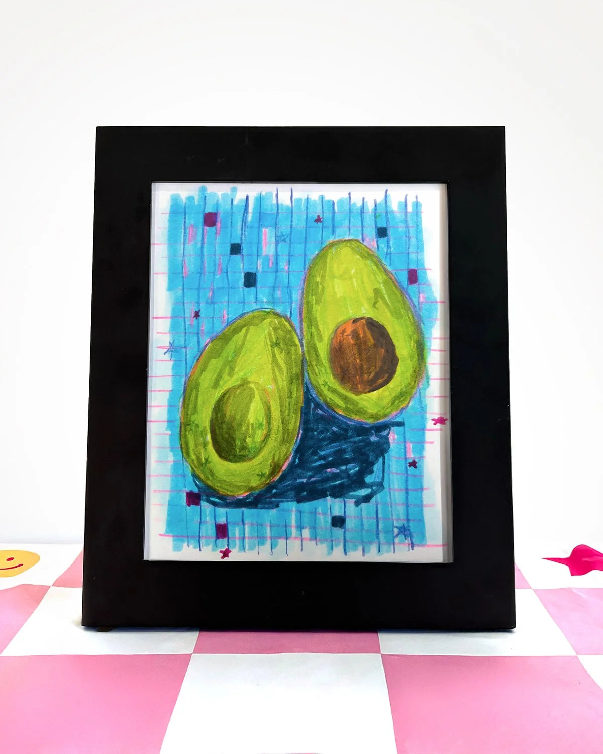 art print of an avocado that was sliced in half on a checkered blue background.