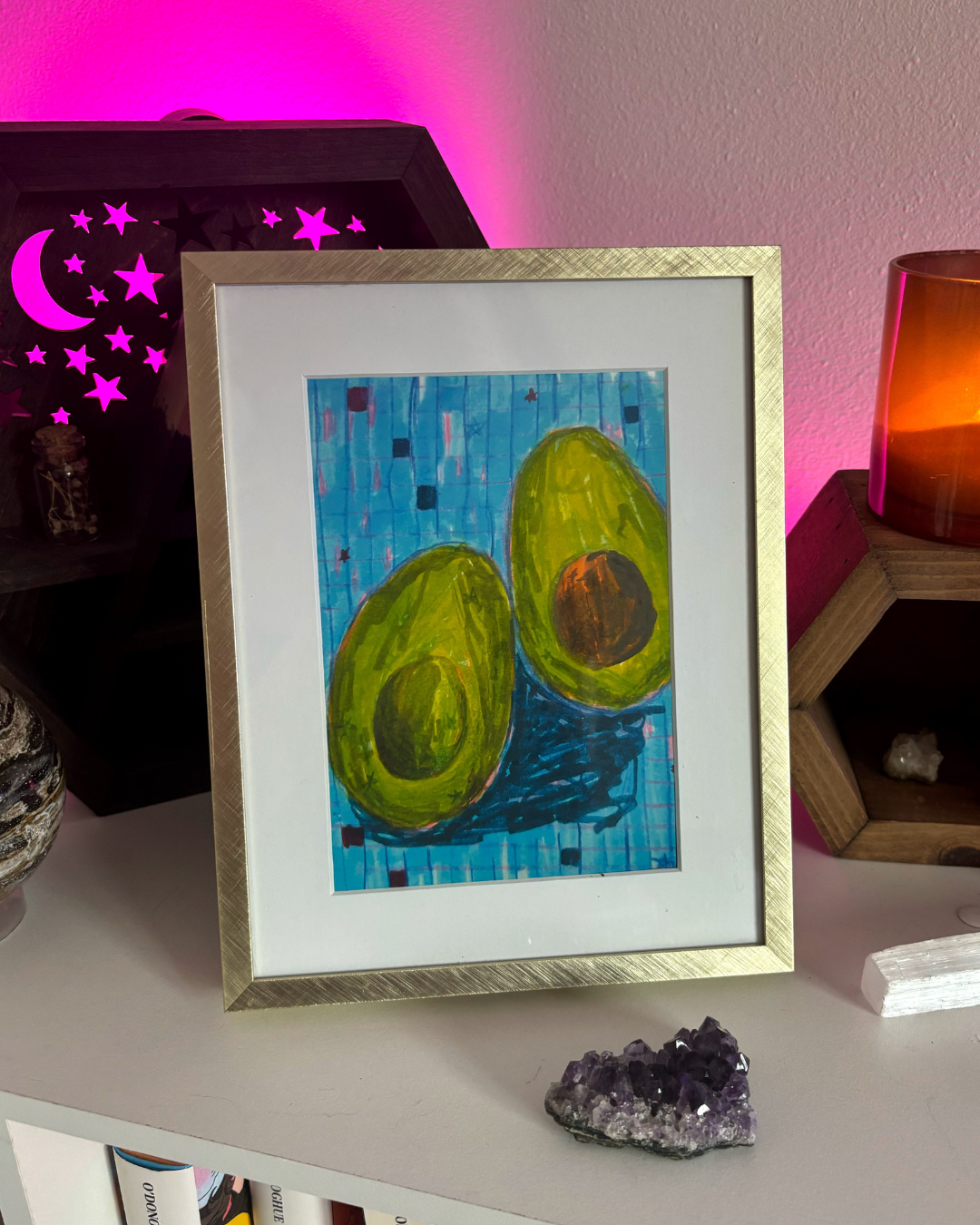art print of an avocado that was sliced in half on a checkered blue background.
