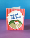 Greeting card with a house illustration and text 'you feel like home' on a striped background